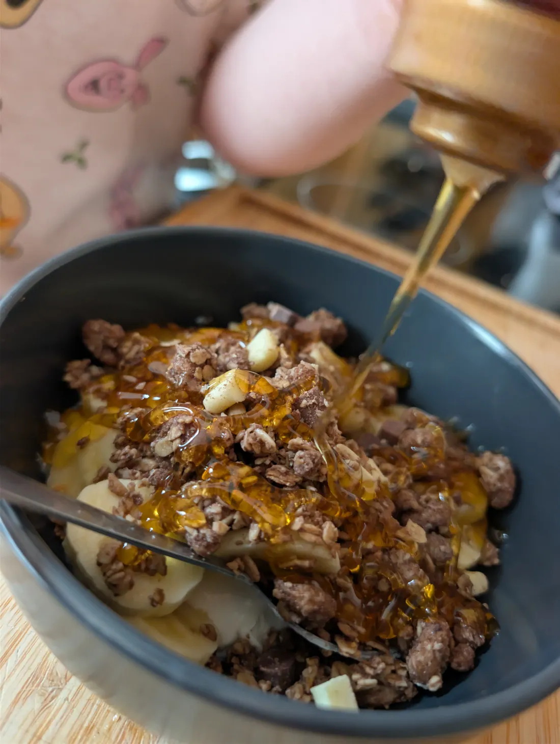 Honey being poured in a golden stream over the granola