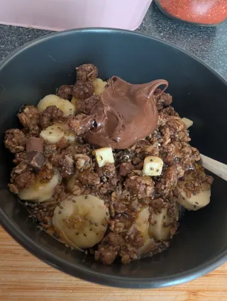 A bowl of yoghurt, banana and granola with a dollop of Nutella